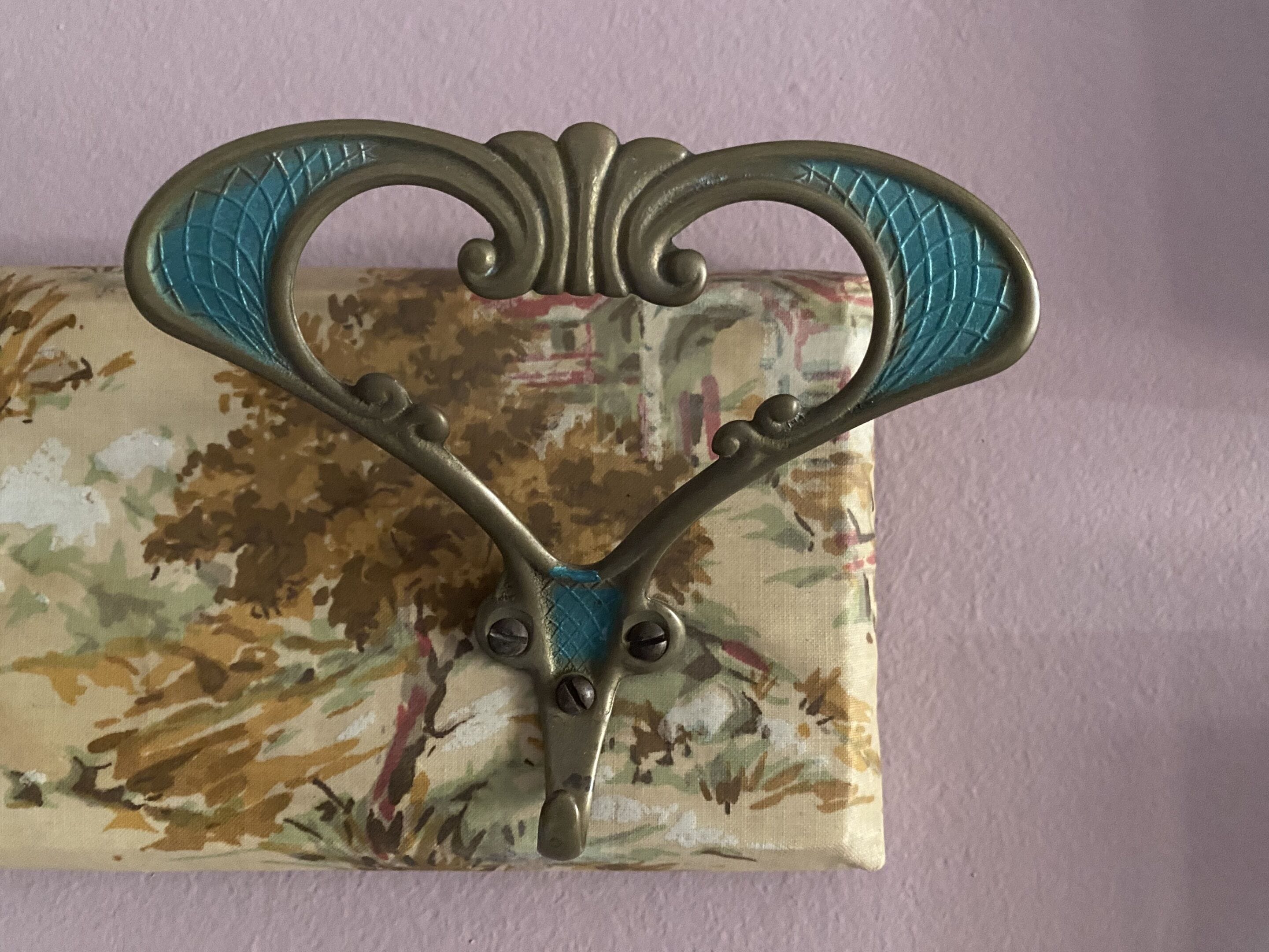 Un maniglia decorativa in metallo su sfondo di tessuto floreale.