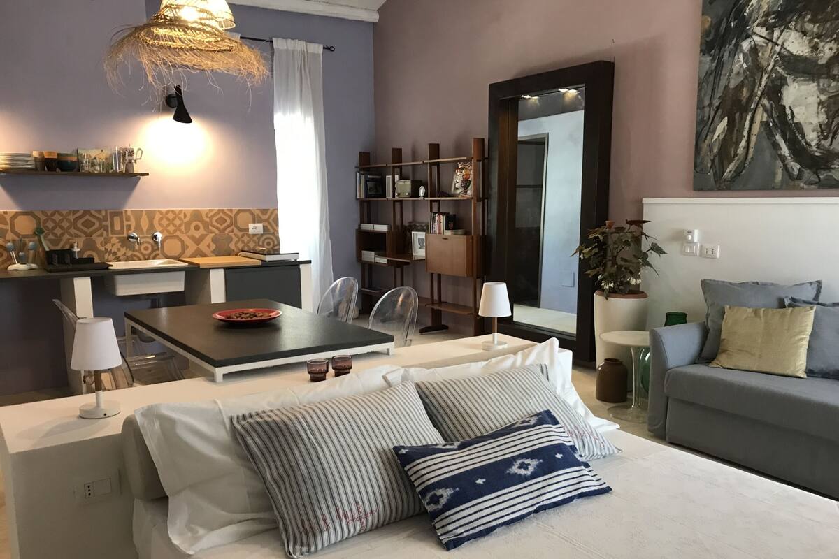 Una sala moderna con un sofá, una mesa de comedor y una cocina al fondo.
