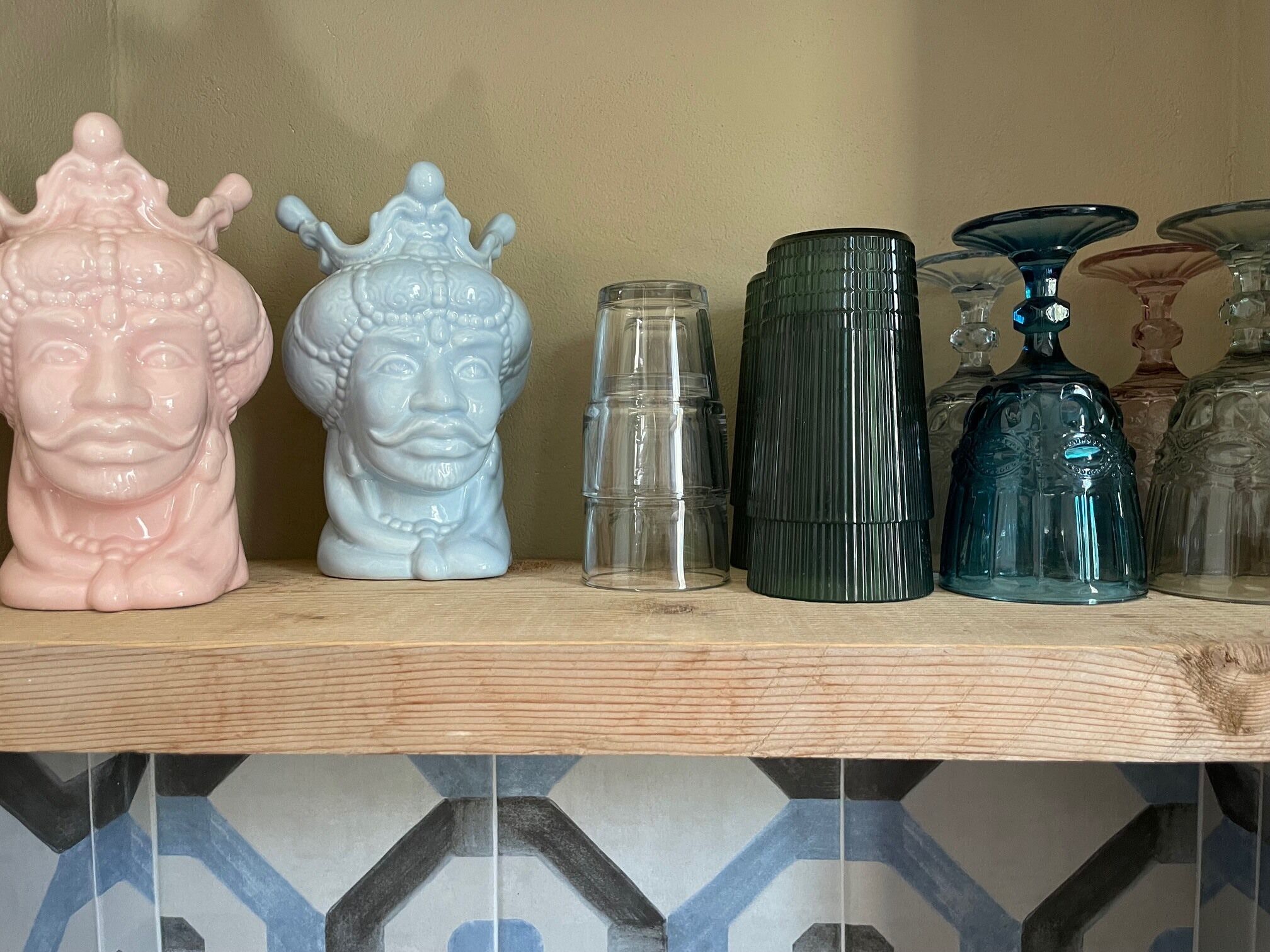 A shelf with various decorative items including ceramic busts and glass containers.