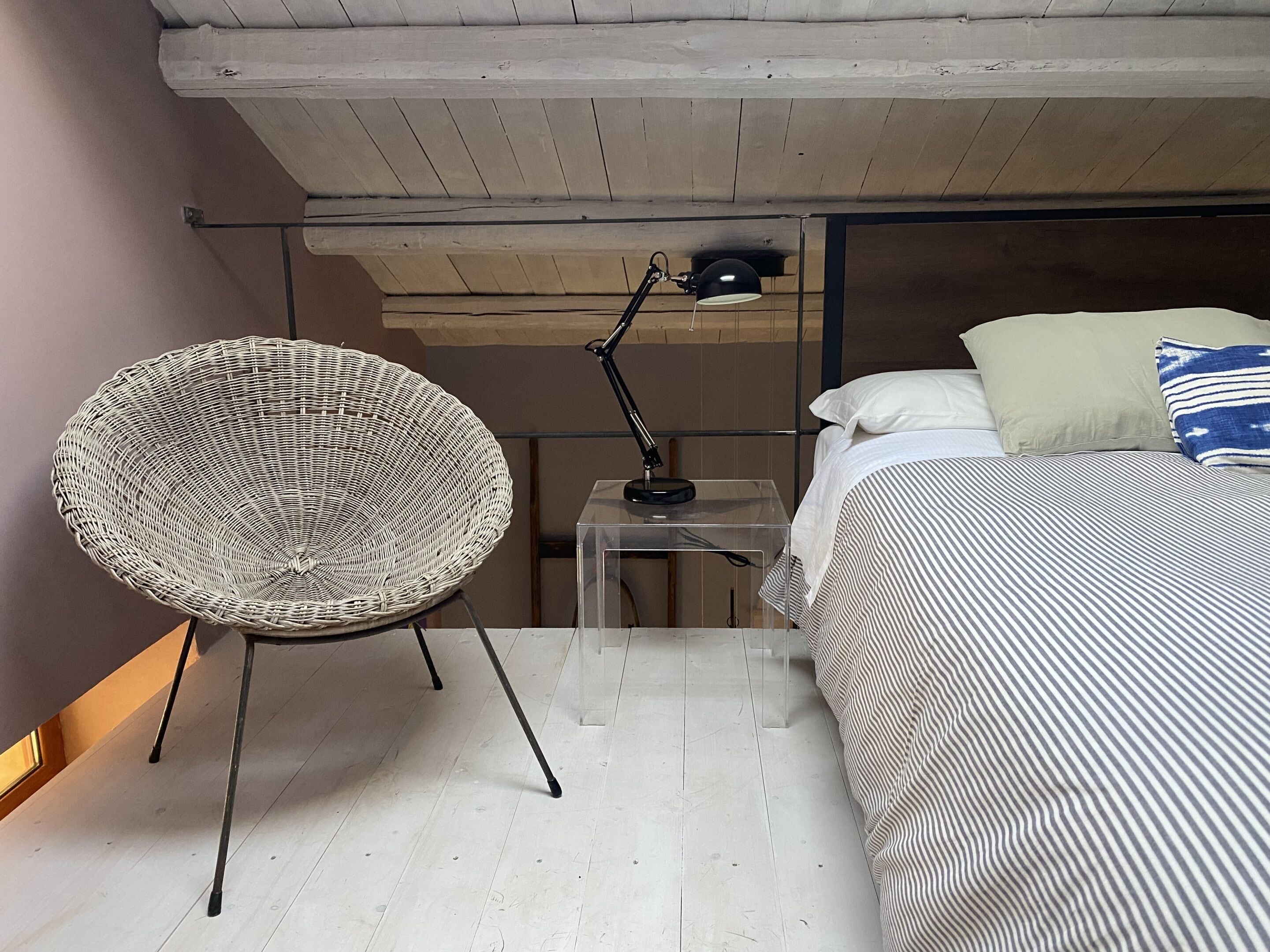 A bedroom with a bed, a chair, a desk, and a lamp.