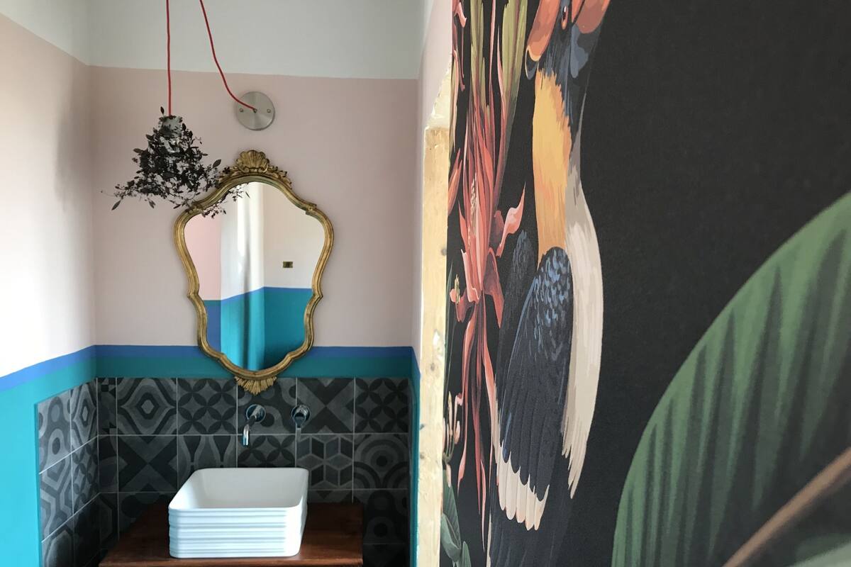 Un baño con lavamanos, espejo y un detalle decorativo en la pared.