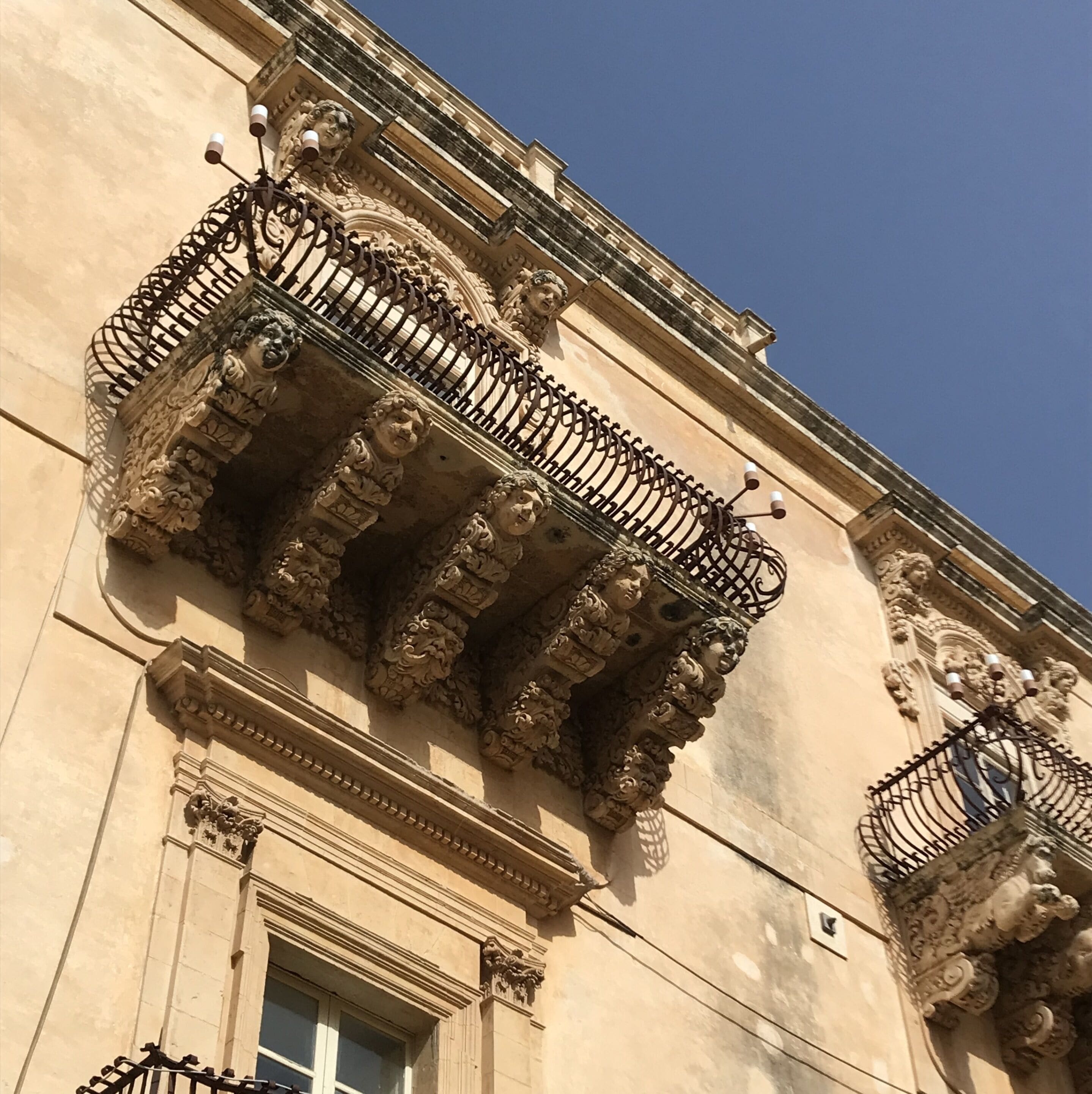Un edificio con balcones ornamentados que lucen intrincados trabajos de metal y detalles arquitectónicos clásicos.