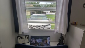 Una habitación con ventana, un cartel de Wi-Fi, una tableta mostrando un paisaje urbano y una pequeña estatua sobre una mesa.