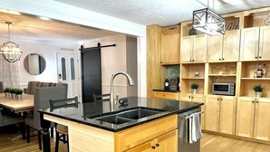 A modern kitchen with wooden cabinets, a black countertop, and a built-in dishwasher. - Hosts groups up to 13; relax with the whole crew at this private, peaceful getaway (Afton)
