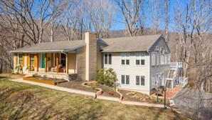 A two-story house with a front porch, a small garden, and a staircase leading to the upper level. - Hosts groups up to 13; relax with the whole crew at this private, peaceful getaway (Afton)