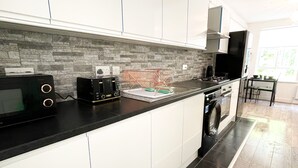 Eine moderne Küche mit weißen Schränken, einer schwarzen Arbeitsplatte und einer Küchenrückwand aus Stein.