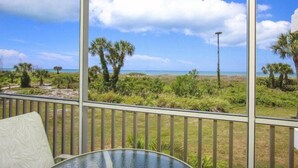 Een balkon met uitzicht op het strand, palmbomen en een heldere lucht.