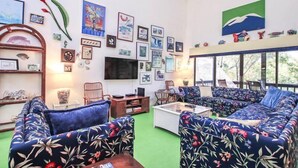 Un salon comprenant un grand canapé, un téléviseur à écran plat et divers tableaux encadrés accrochés aux murs.