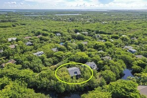 An aerial view of a residential area with houses surrounded by dense greenery and water bodies. - Gulf Pines Too (Sanibel)
