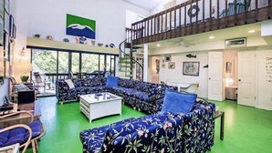 Un vaste espace de vie comprenant un grand canapé, une table basse et un escalier menant à un niveau supérieur.