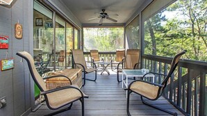 Un espace extérieur abrité, doté de chaises et de tables, de grandes fenêtres et d’un ventilateur de plafond.