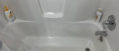 Una bañera blanca con dos llaves y un desagüe.