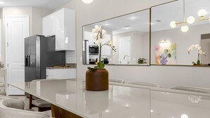A modern kitchen with a large island, white cabinets, and a large mirror. - 4 BD/ 4 BA/ Formosa Valley (7973 FV) (Kissimmee)