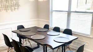 Un salón de conferencias con una mesa grande, sillas negras y una lámpara de araña moderna.