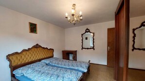 Ein Schlafzimmer mit einem großen Bett, einer Kristallleuchtre, einem Spiegel und einer Holztür.