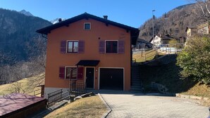 Ein zweistöckiges Gebäude mit roter Fassade, einem Hauseingang und einem kleinen Balkon.