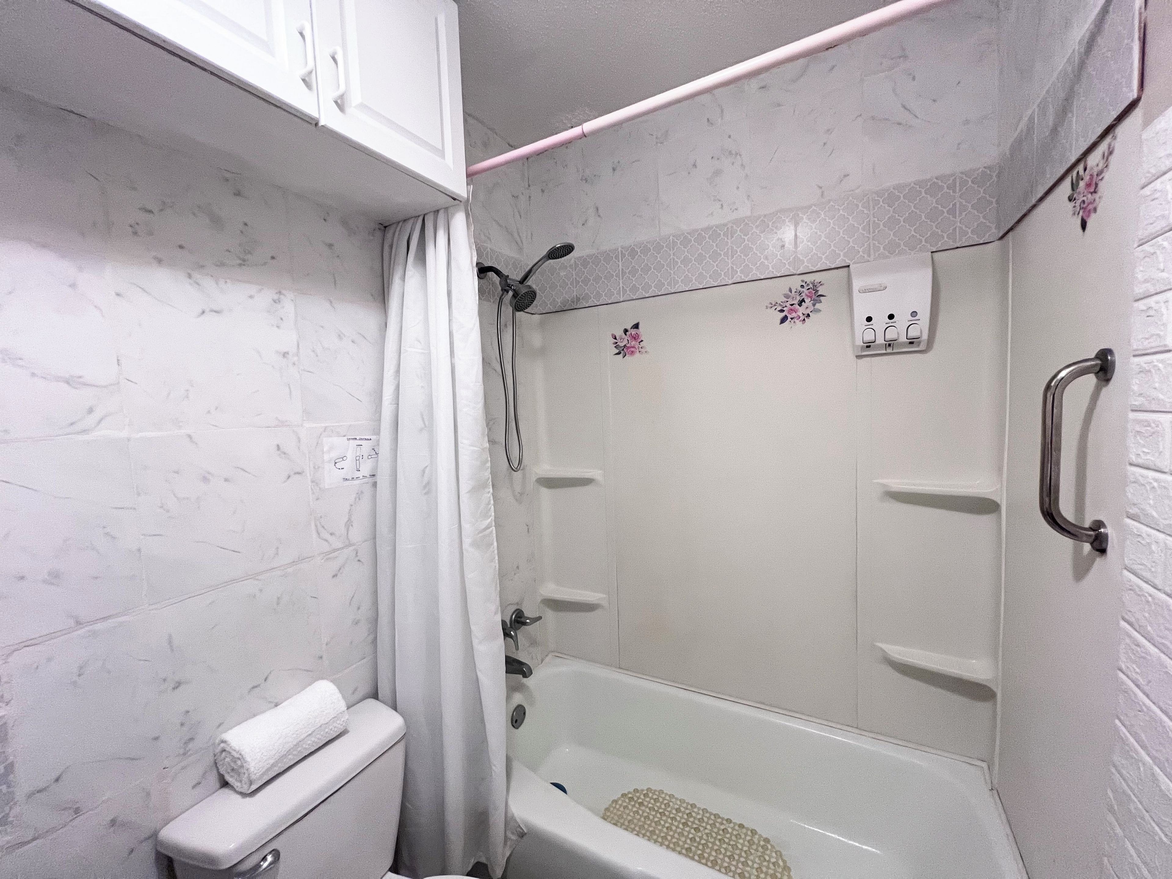 A bathroom with a bathtub, toilet, and shower area.