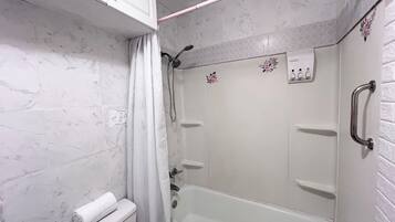A bathroom with a bathtub, toilet, and shower area.