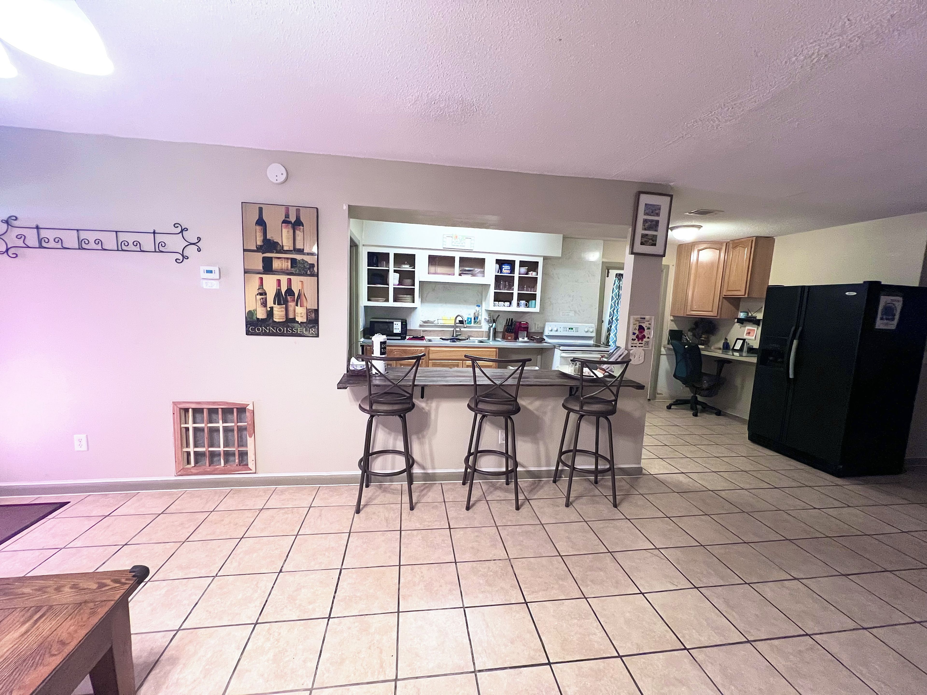 A kitchen with a bar area, a refrigerator, and a microwave.