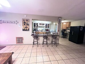 A kitchen with a bar area, a refrigerator, and a microwave.