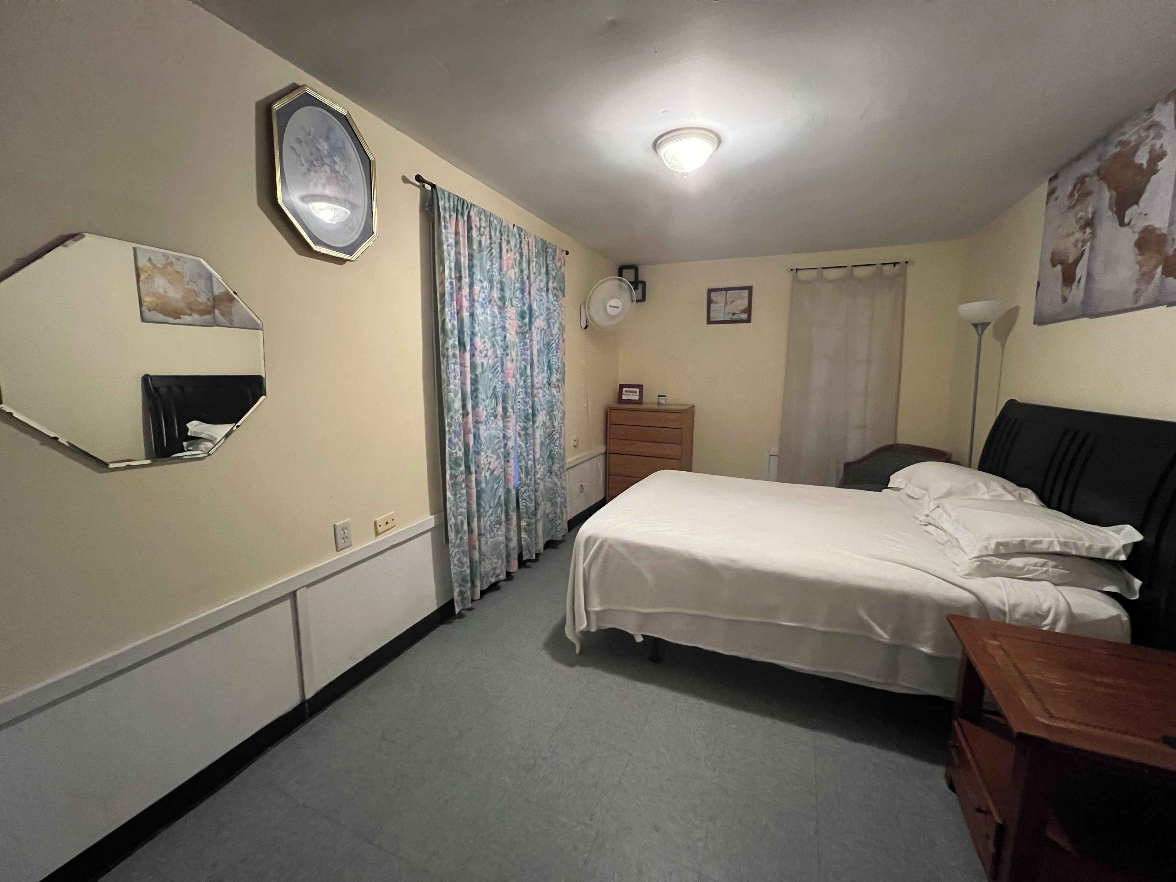 Une chambre à coucher avec un lit, une commode, un miroir et un luminaire au plafond.