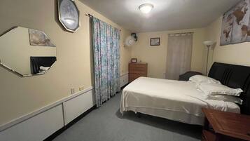 Une chambre à coucher avec un lit, une commode, un miroir et un luminaire au plafond.