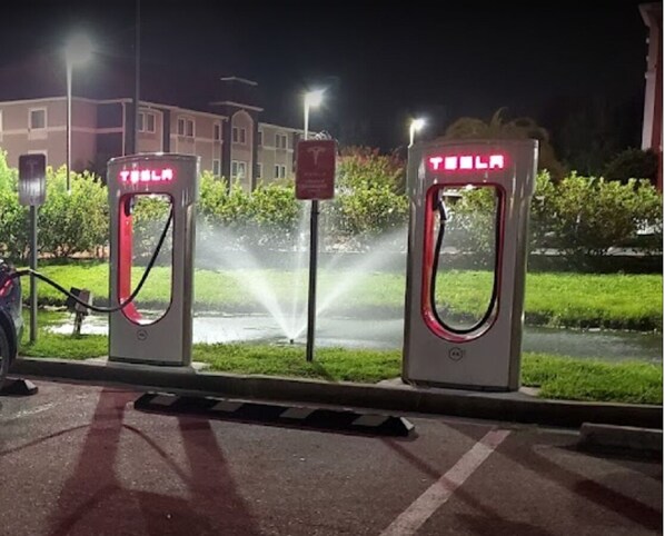 Two Tesla charging stations at night with a building and greenery in the background. - 3BR Home • 1 Mile to I-95 • Large Parking (Kingsland)