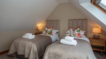 A bedroom with two beds, each with a quilted bedspread and pillows, and bedside lamps.