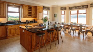 Una cocina amplia con armarios de madera, una isla grande con taburetes y un comedor con vistas al paisaje.