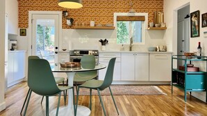 A modern kitchen with white cabinets, a dining table with chairs, and a window with a view of greenery. - Renovated Retro Bungalow - Walk to Downtown! (Prescott)