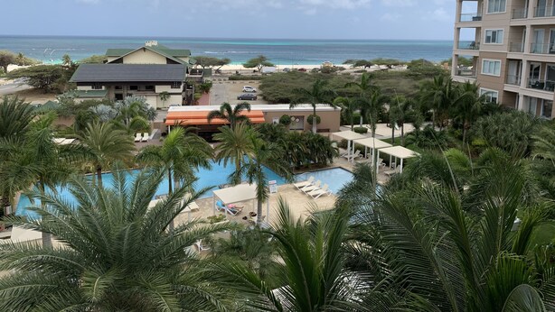 Een resort met een zwembad, palmbomen en uitzicht op de oceaan.