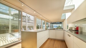 A modern kitchen with a large island, white cabinetry, and a view of the outdoors. - Seafront Villa Sunset Alcudia by Balearic Villas (Alcúdia)