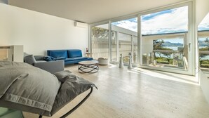 A modern living room with a large sliding glass door leading to a balcony with a scenic view. - Seafront Villa Sunset Alcudia by Balearic Villas (Alcúdia)