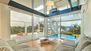 A modern living room with a large glass door leading to a balcony with a pool. - Seafront Villa Sunset Alcudia by Balearic Villas (Alcúdia)