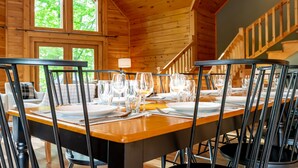 Un interior de madera con una mesa de comedor lista para seis personas, con platos, vasos y cubiertos.