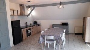 Een moderne keuken met een eethoek, met een zwarte koelkast, houten kastjes, een magnetron en een tafel met stoelen.