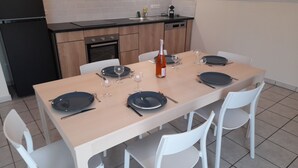 Een eethoek met een tafel voor vier personen, compleet met borden, bestek en wijnglazen.