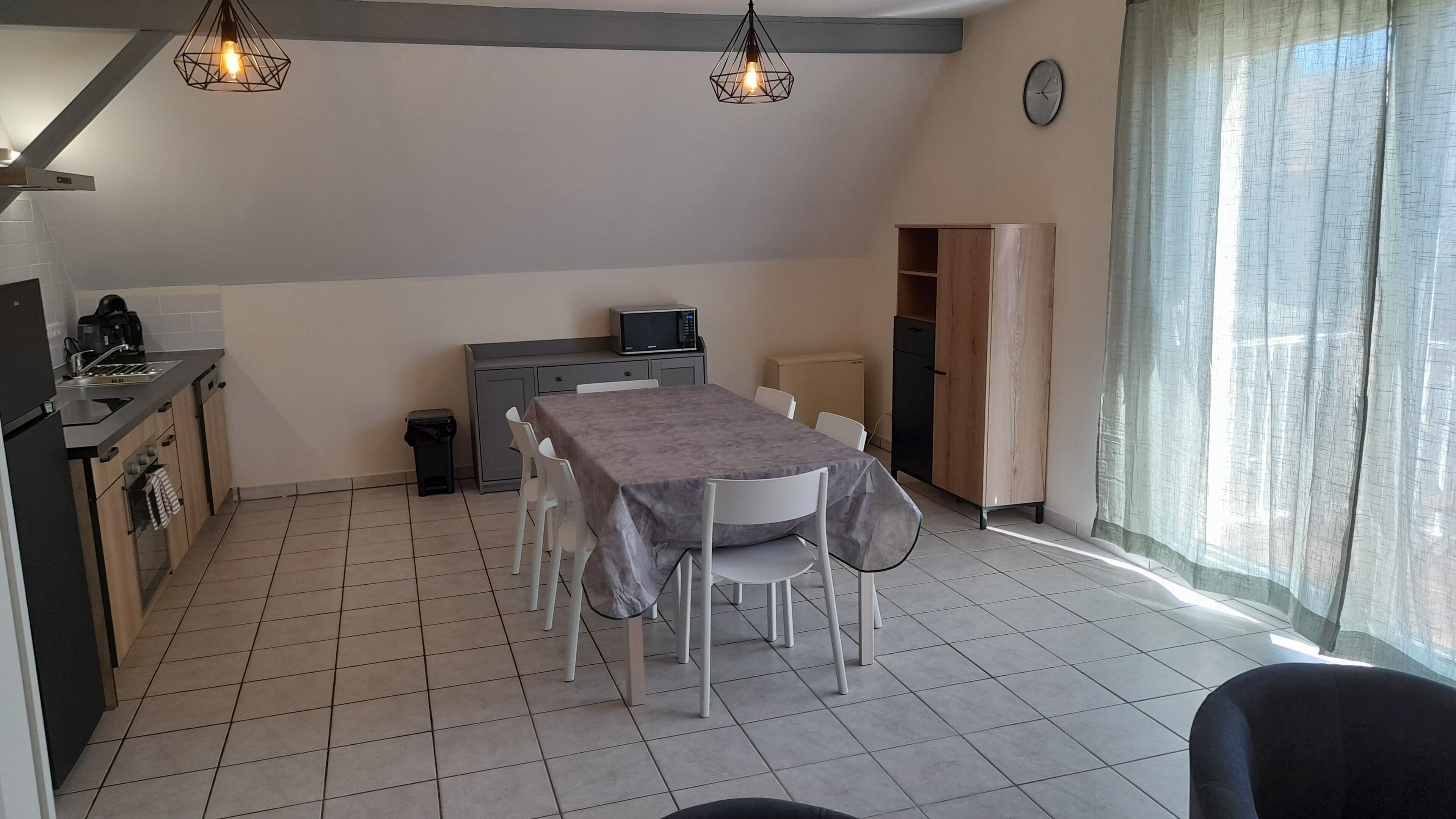 Een kleine keuken met een eettafel, stoelen, een magnetron en een koelkast.