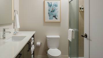 A modern bathroom with a white sink, toilet, and glass shower enclosure.