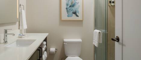 A modern bathroom with a white sink, toilet, and glass shower enclosure.