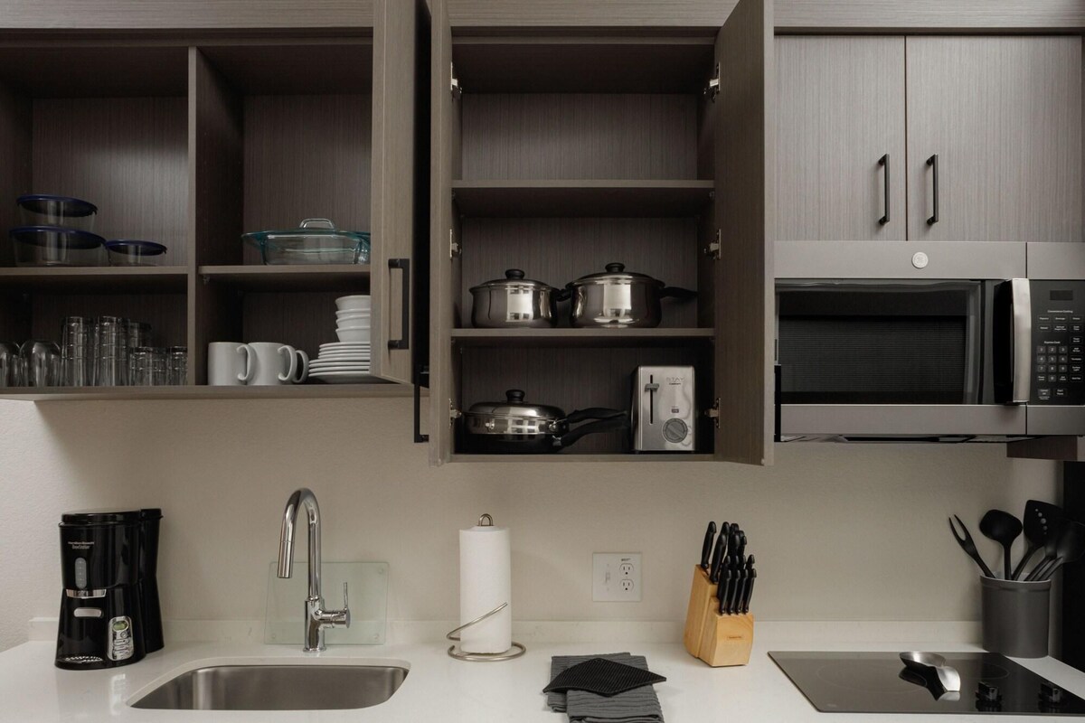 A modern kitchen with a built-in microwave, a coffee maker, and a sink.