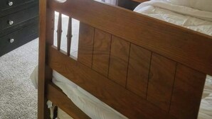 A bedroom with a wooden bed, a dresser, a television on top of the dresser, and a window with curtains. - Midcentury modern home 5min from Riverfront park (Spokane)