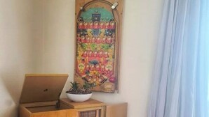 A corner room with a wooden cabinet, a bowl on top, and a colorful pinball machine on the wall. - Midcentury modern home 5min from Riverfront park (Spokane)