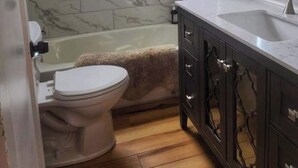 A bathroom with a toilet, bathtub, and a vanity with a sink. - Midcentury modern home 5min from Riverfront park (Spokane)