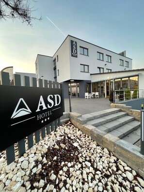 The exterior of the ASD Hotel with a modern design, featuring a prominent entrance and a landscaped area with stepping stones. - ASD Hotel (Filderstadt)