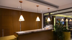 A reception area with wooden paneling, a marble counter, and pendant lighting.