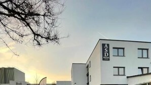 A sign for ASD Hotel with a modern building in the background.