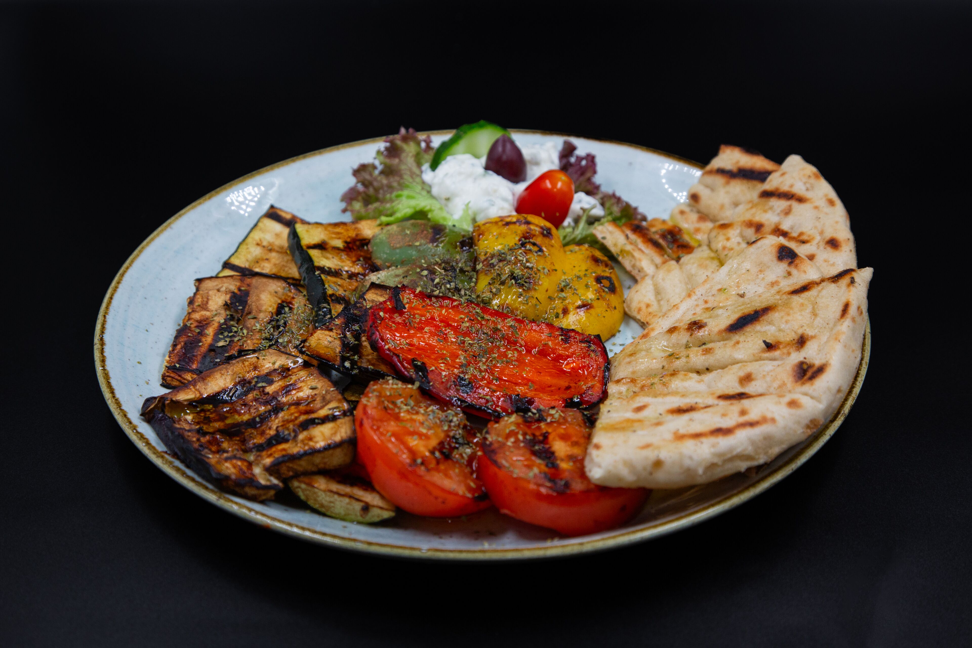 A plate of grilled vegetables and flatbread.
