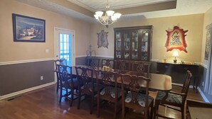 A dining room with a wooden table and chairs, a chandelier, and a cabinet with glass doors. - Minutes from Churchill Downs & Downtown Lou! (Louisville)