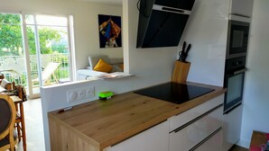 A modern kitchen with a wooden countertop, white cabinets, a built-in oven, and a microwave. - Beautiful apartment at the gateway to the Medoc (BRUGES)